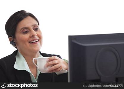 Smiling businesswoman drinking coffee while working