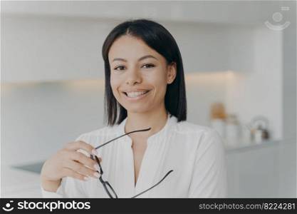 Smiling businesswoman, female business coach, manager holding glasses, looking at camera in office. Happy confident woman, corporate leader, boss, posing on workplace for corporate company portrait.. Smiling businesswoman, female business coach, manager holding glasses, looking at camera in office