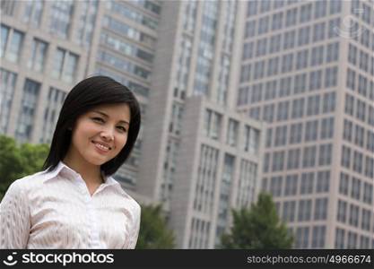 Smiling businesswoman near an office building