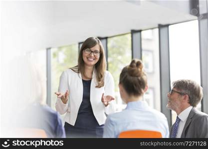 Smiling businesswoman planning strategy with colleagues during meeting at office
