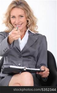 Smiling businesswoman pointing her pen at the camera