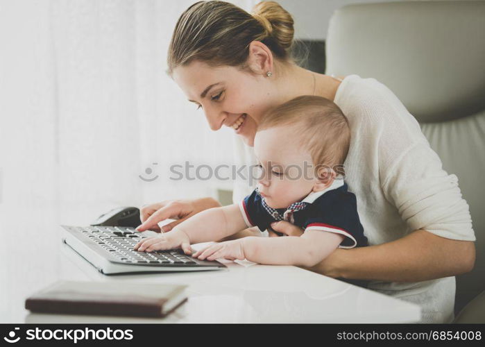 Smiling businesswoman posing with her baby at office