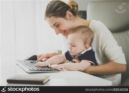 Smiling businesswoman posing with her baby at office