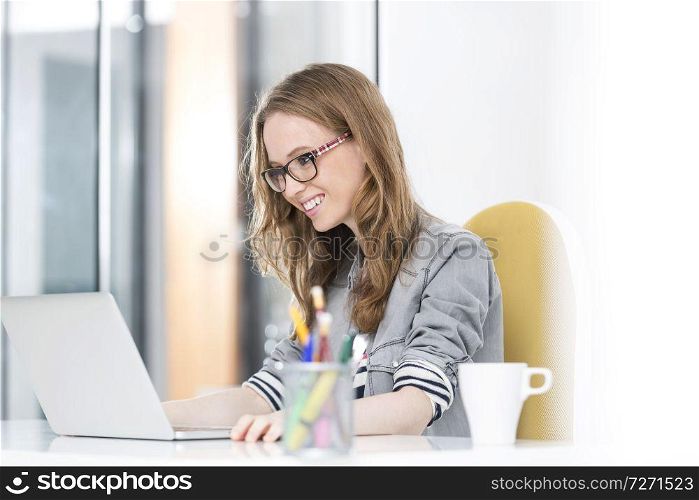 Smiling businesswoman reading an email on laptop in office