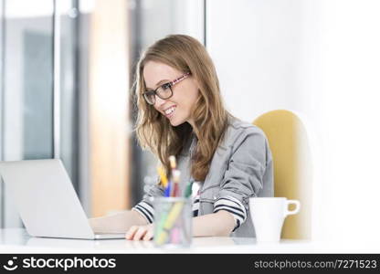 Smiling businesswoman reading an email on laptop in office