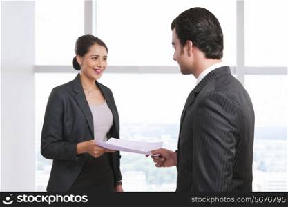 Smiling businesswoman receiving document from colleague in office
