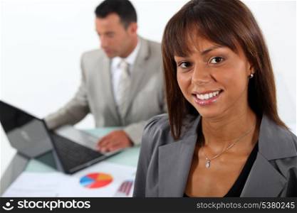 Smiling businesswoman standing in front of a colleague and his laptop
