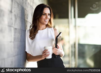 Smiling businesswoman taking a coffee break in an office building. Young woman with california highlights in her hair.. Smiling businesswoman taking a coffee break in an office building.