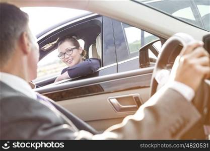 Smiling businesswoman talking to executive while sitting in car