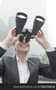Smiling Businesswoman Using Binoculars Outside in Beijing, Looking Up