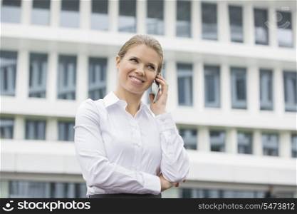 Smiling businesswoman using cell phone outside office