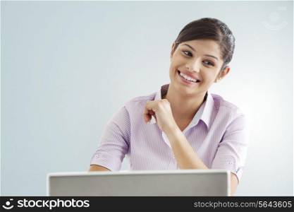 Smiling businesswoman using laptop over colored background