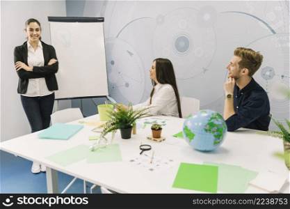 smiling businesswoman with folded hands standing near flipchart meeting