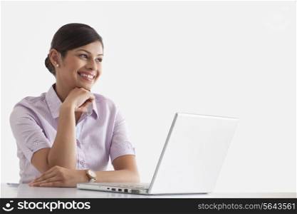 Smiling businesswoman with laptop looking away