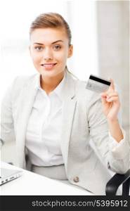 smiling businesswoman with laptop showing credit card