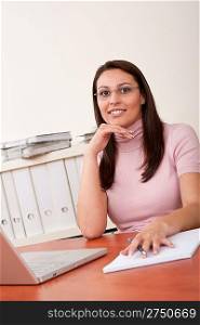 Smiling businesswoman with laptop sitting at office