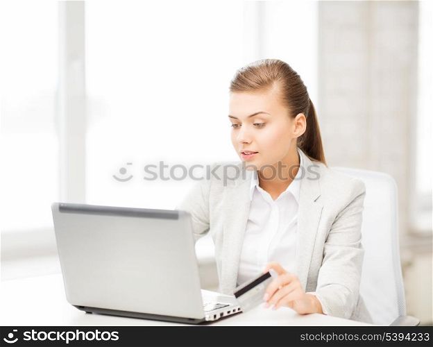 smiling businesswoman with laptop using credit card