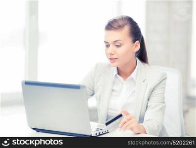 smiling businesswoman with laptop using credit card. businesswoman with laptop using credit card