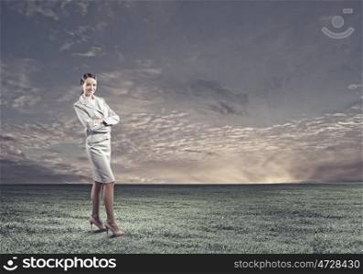 Smiling businesswoman. Young attractive businesswoman standing on green field
