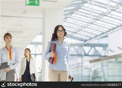 Smiling businesswomen with luggage and file walking at airport