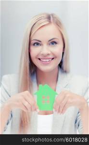 smiling busineswoman with green eco house symbol. woman with illustration of eco house