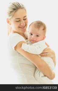 Smiling caring mother cuddling her 3 months old baby at big window at sunny day