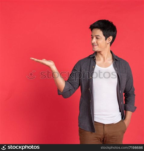 smiling casual young asian man or student collage university welcoming invite hand isolated on red studio background