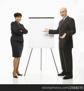 Smiling Caucasian middle-aged businessman and Filipino businesswoman standing making presentation against white background.