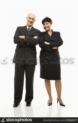 Smiling Caucasian middle-aged businessman and Filipino businesswoman standing with arms crossed against white background.