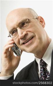 Smiling Caucasian middle-aged businessman talking on cellphone against white background.