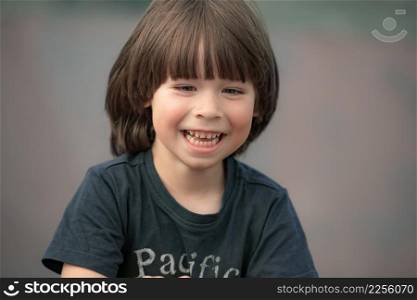 Smiling child face portrait on blurry background, looking away from camera