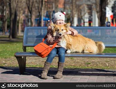 smiling child girl with dog sitting on a bench