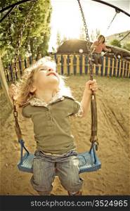 Smiling child on swing on playground. Vintage look. Shot was taken with fisheye lens
