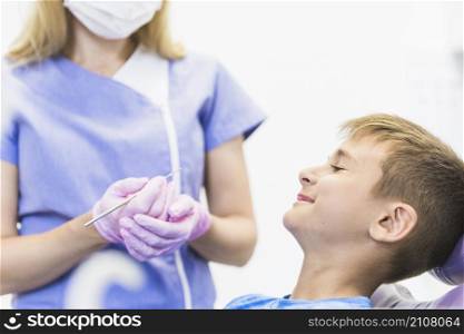 smiling child patient front female dentist holding scaler