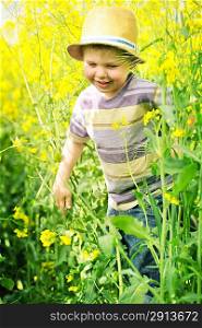 Smiling child running among the canola flowers