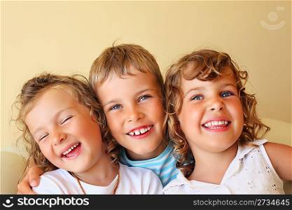 Smiling children three together in cosy, girl at left closed eyes