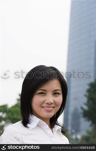 Smiling Chinese woman near skyscrapers