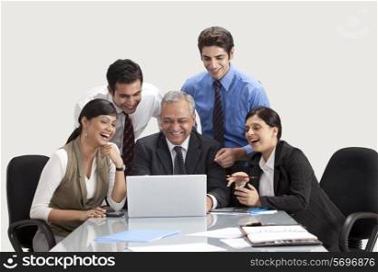 Smiling colleagues at table with laptop
