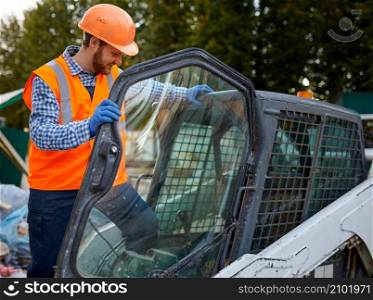 Smiling construction worker driving vehicle sitting in cab. Heavy equipment operator closeup shot. Construction worker in vehicle cab closeup shot