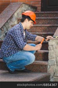 Smiling construction worker repairing stone staircase