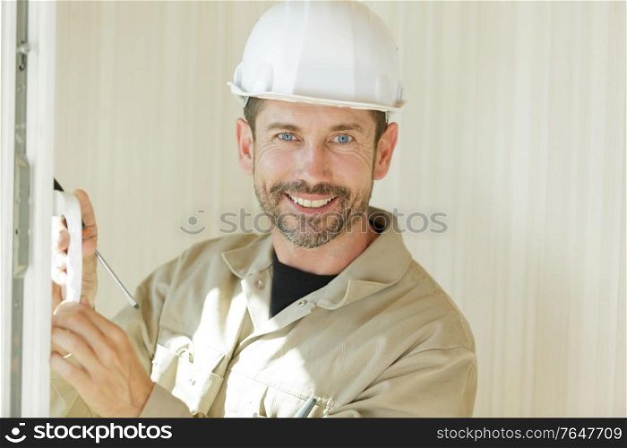 smiling construction worker stood by window