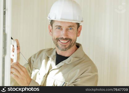 smiling construction worker stood by window