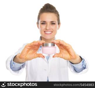 Smiling cosmetologist woman showing bottle of creme