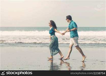 smiling couple barefoot walking along beach