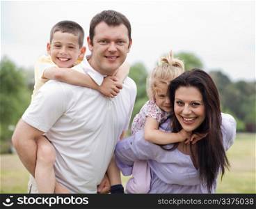 Smiling couple carrying kids on their back over natural background
