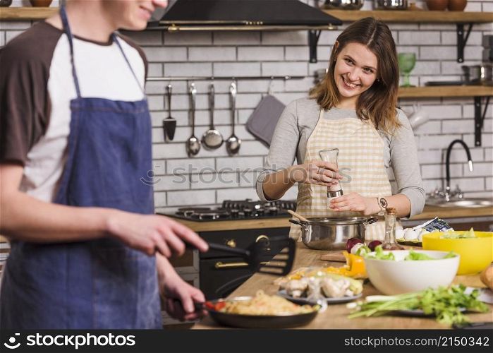smiling couple cooking dishes together