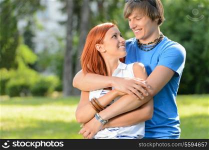 Smiling couple embracing looking at each other in sunny park