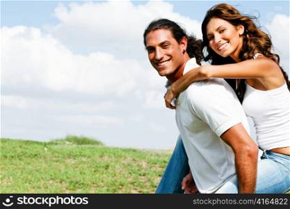Smiling couple enjoying piggyback ride on nature background