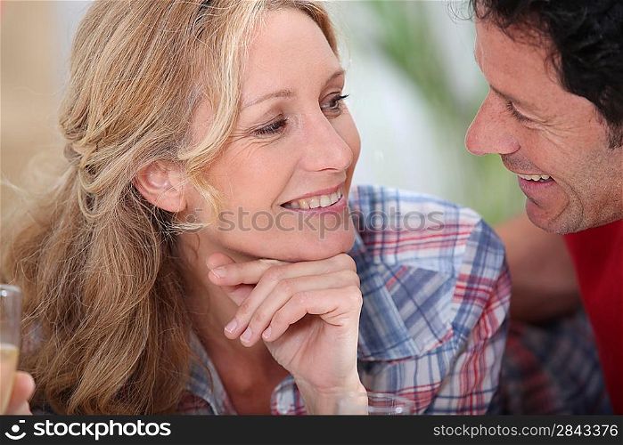 Smiling couple gazing intimately at each other with champagne glasses just in sight