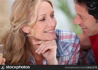Smiling couple gazing intimately at each other with champagne glasses just in sight